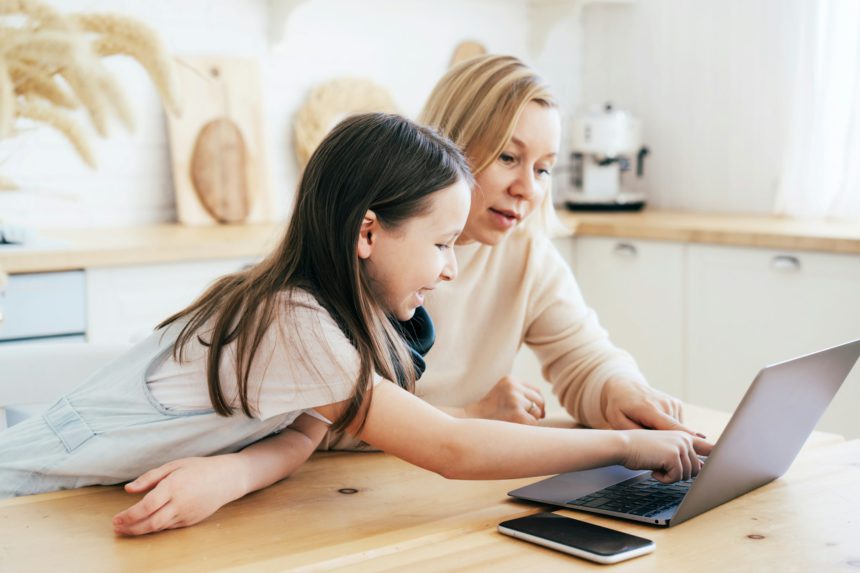 Mom and daughter surf in a laptop. Business woman with her daughter. Remote work.